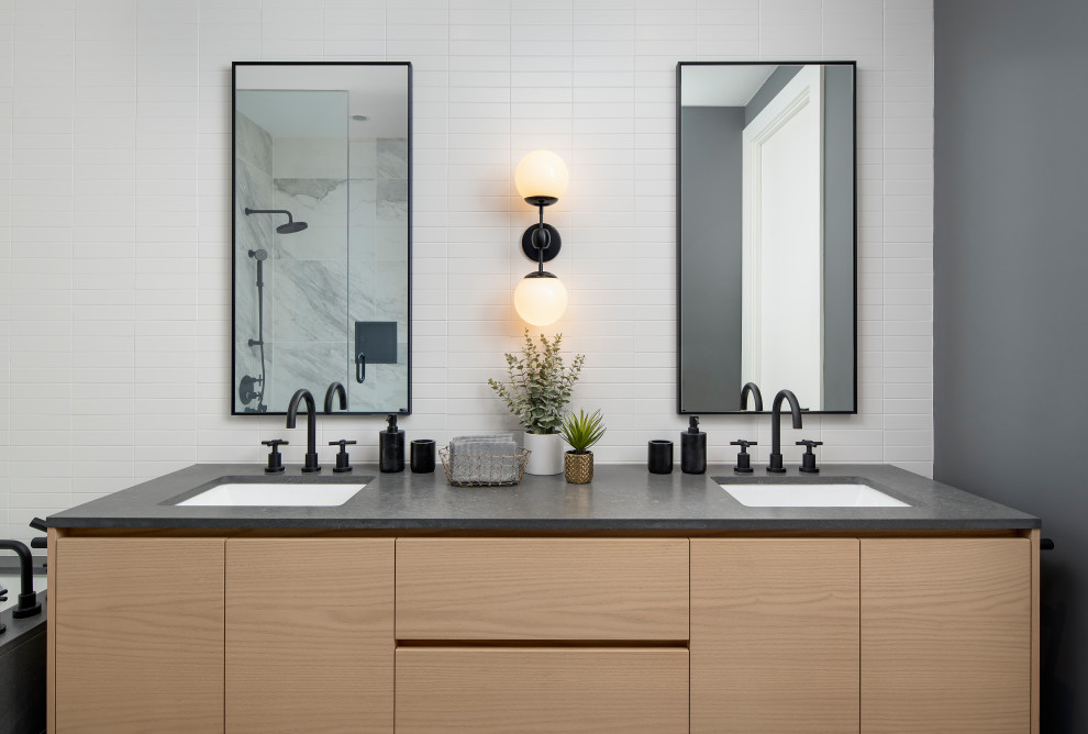 Inredning av ett skandinaviskt mellanstort grå grått en-suite badrum, med släta luckor, skåp i ljust trä, ett undermonterat badkar, en dusch i en alkov, en toalettstol med hel cisternkåpa, vit kakel, keramikplattor, grå väggar, klinkergolv i keramik, ett undermonterad handfat, träbänkskiva och dusch med gångjärnsdörr