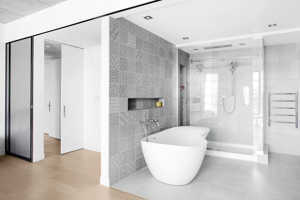 Immagine di una stanza da bagno minimal con vasca freestanding, doccia ad angolo, piastrelle grigie, pavimento grigio e porta doccia scorrevole