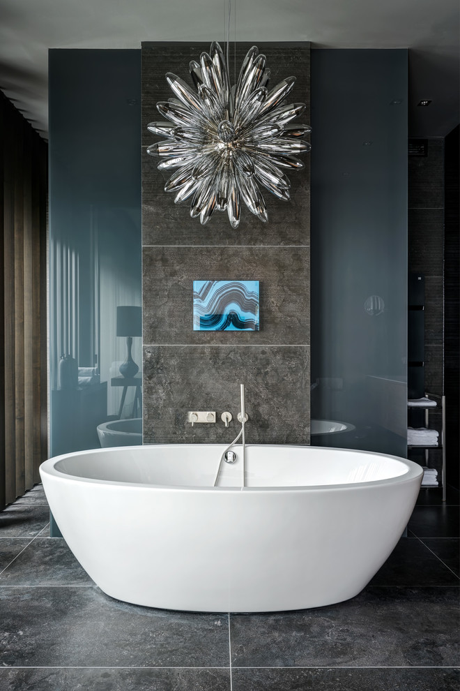 Modern inredning av ett en-suite badrum, med ett fristående badkar, svart golv och svart kakel