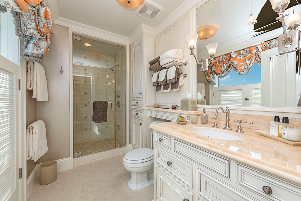 マイアミにあるトラディショナルスタイルのおしゃれなバスルーム (浴槽なし) (白いキャビネット、洗い場付きシャワー、白いタイル、ベージュの壁、アンダーカウンター洗面器、ベージュの床、開き戸のシャワー、落し込みパネル扉のキャビネット) の写真