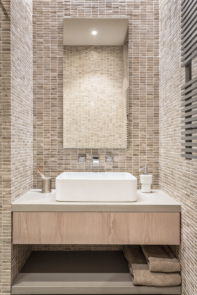 На фото: ванная комната в современном стиле с настольной раковиной, плоскими фасадами, светлыми деревянными фасадами, бежевой плиткой и каменной плиткой