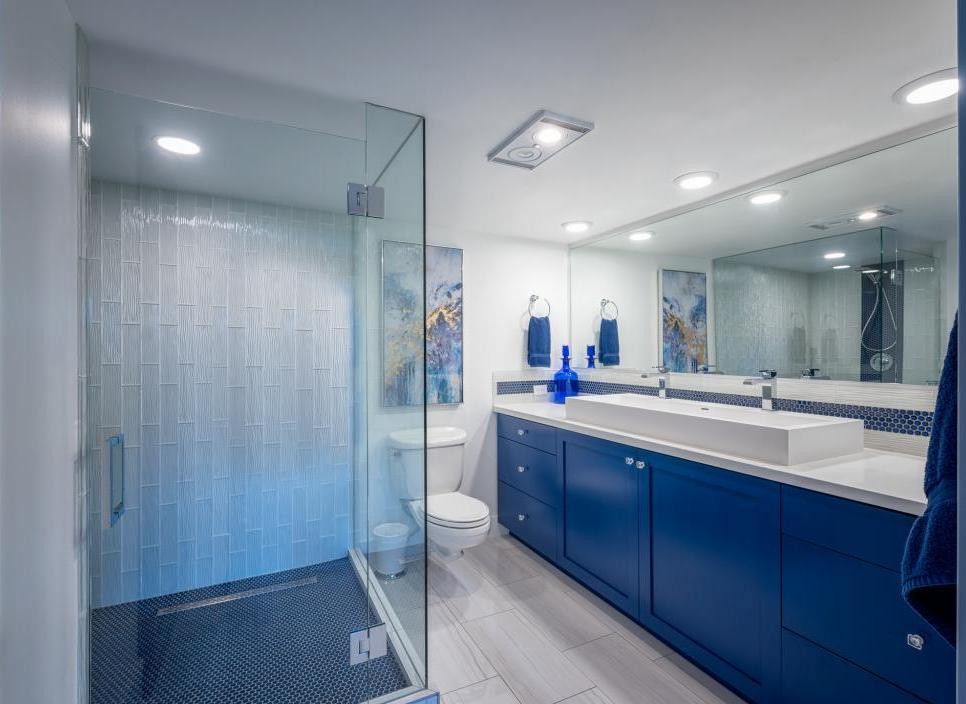 Idéer för ett mellanstort modernt vit en-suite badrum, med skåp i shakerstil, blå skåp, en hörndusch, en vägghängd toalettstol, blå kakel, glaskakel, vita väggar, travertin golv, ett avlångt handfat, bänkskiva i kvarts, beiget golv och dusch med gångjärnsdörr