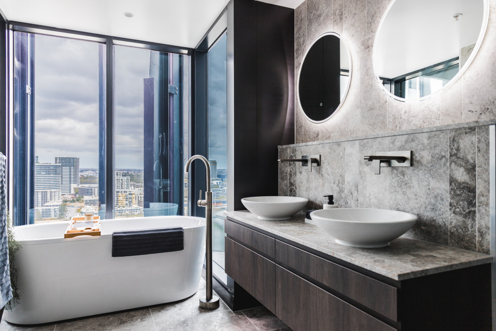 Trendy gray tile gray floor and double-sink freestanding bathtub photo in Sydney with flat-panel cabinets, gray cabinets, a vessel sink, gray countertops and a floating vanity