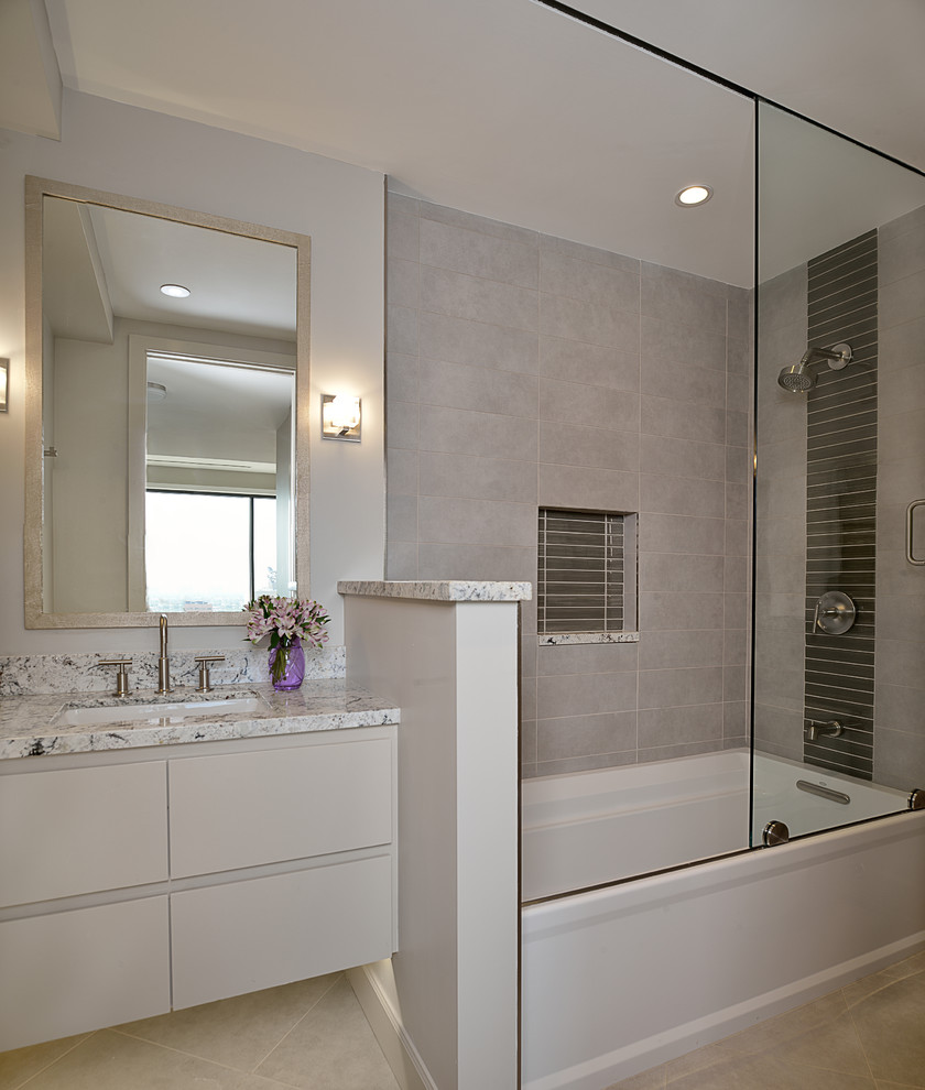 Idéer för ett mellanstort modernt en-suite badrum, med ett undermonterad handfat, släta luckor, grå skåp, granitbänkskiva, ett badkar i en alkov, en dusch/badkar-kombination, en toalettstol med separat cisternkåpa, grå kakel, porslinskakel, grå väggar och klinkergolv i porslin