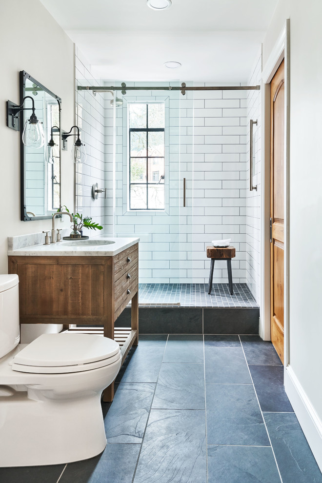 Foto på ett litet vintage grå badrum med dusch, med skåp i slitet trä, en toalettstol med separat cisternkåpa, vit kakel, keramikplattor, vita väggar, ett konsol handfat, marmorbänkskiva och släta luckor