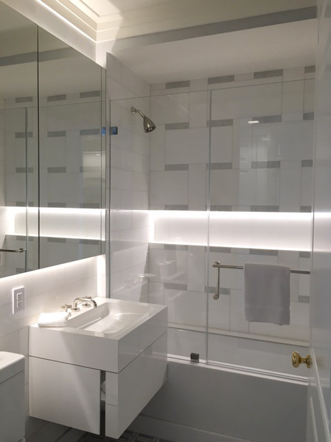 Exemple d'une salle de bain moderne de taille moyenne pour enfant avec des portes de placard blanches, une baignoire encastrée, un combiné douche/baignoire, WC à poser, un carrelage blanc, un carrelage de pierre, un mur gris, un sol en marbre et un lavabo suspendu.