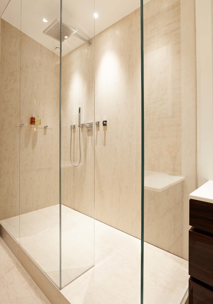 Example of a large trendy master beige tile and stone slab limestone floor bathroom design in London with an integrated sink, flat-panel cabinets, dark wood cabinets, solid surface countertops, a one-piece toilet and white walls