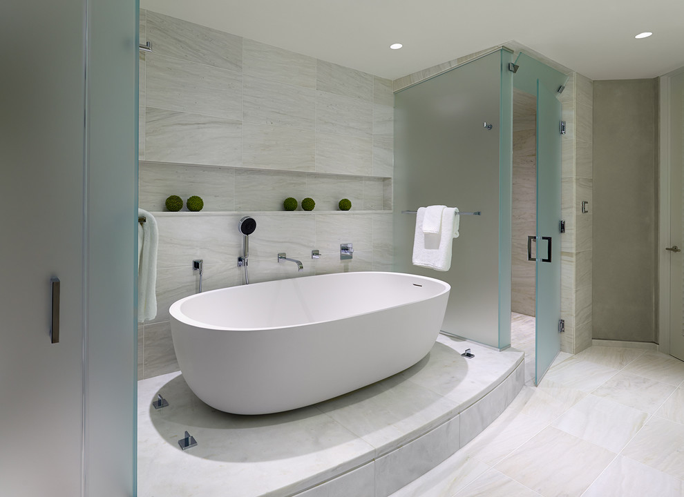 Photo of a medium sized contemporary ensuite bathroom in DC Metro with flat-panel cabinets, white cabinets, a freestanding bath, an alcove shower, beige tiles, beige walls, marble flooring, a submerged sink and marble worktops.