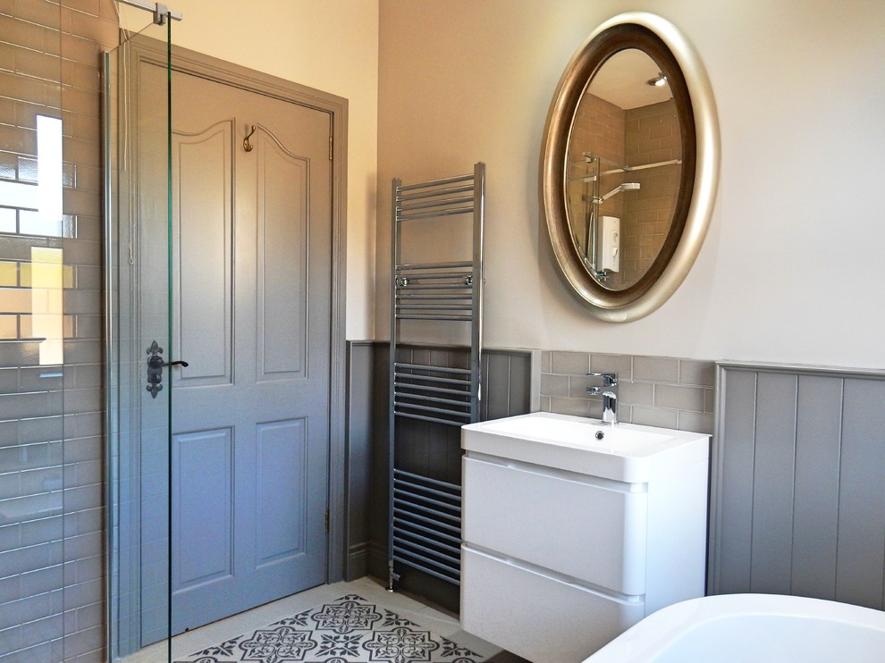 Exemple d'une salle de bain chic de taille moyenne pour enfant avec une baignoire indépendante, un espace douche bain, WC à poser, un carrelage gris, des carreaux de porcelaine, un mur gris, un sol en carrelage de porcelaine, un lavabo suspendu et un sol gris.