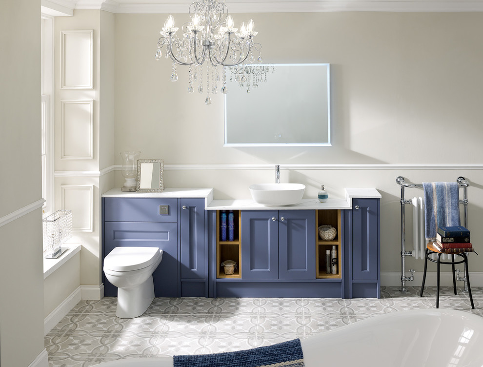 Klassisk inredning av ett vit vitt badrum för barn, med skåp i shakerstil, blå skåp, ett fristående badkar, en toalettstol med hel cisternkåpa, klinkergolv i porslin, ett fristående handfat, bänkskiva i akrylsten, grått golv och beige väggar