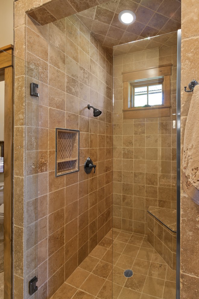 Réalisation d'une douche en alcôve chalet avec un plan de toilette en granite, une baignoire posée, un carrelage beige et un carrelage de pierre.