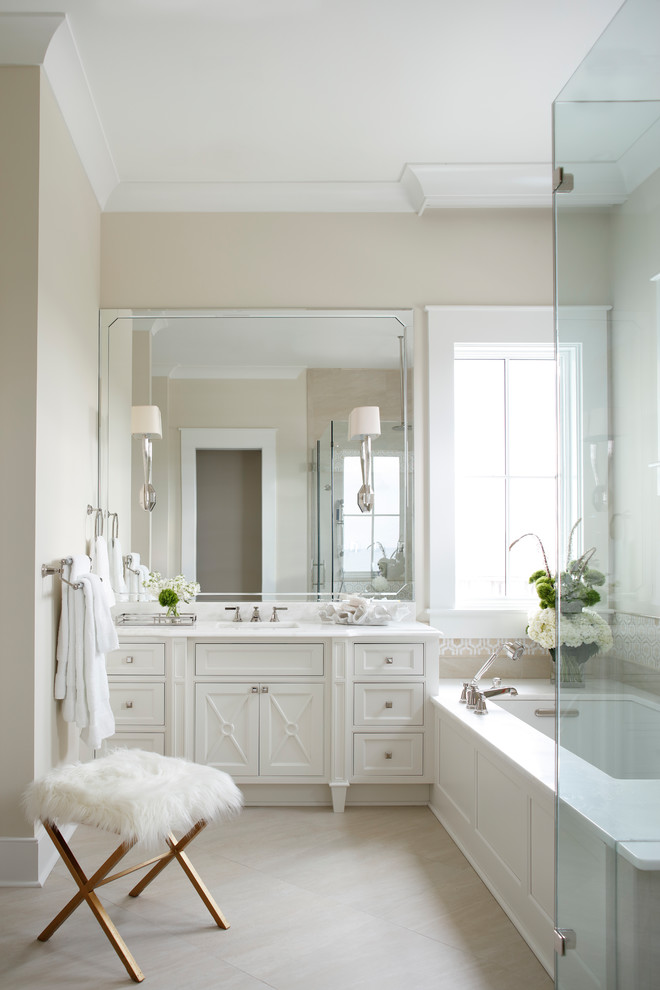 Свежая идея для дизайна: большая главная ванная комната в морском стиле с белыми фасадами, врезной раковиной, мраморной столешницей, фасадами с декоративным кантом, полновстраиваемой ванной, угловым душем, бежевыми стенами и зеркалом с подсветкой - отличное фото интерьера