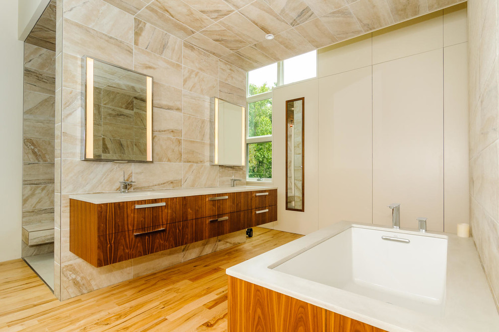 Cette photo montre une salle de bain moderne en bois foncé avec un placard à porte plane, une baignoire encastrée, un carrelage beige, un mur beige et un sol en bois brun.