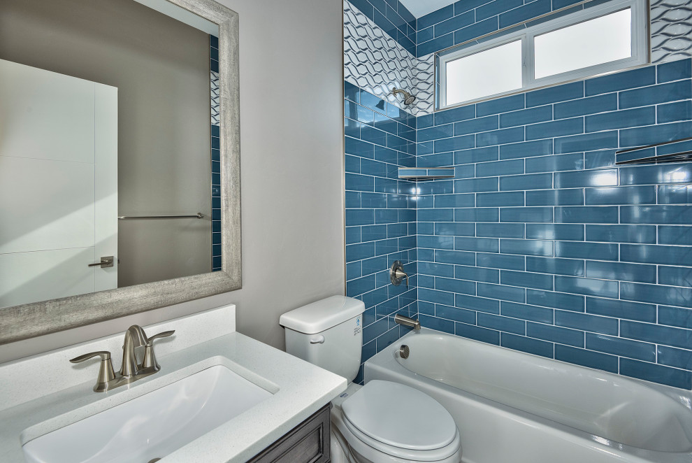 Exemple d'une salle de bain tendance en bois vieilli de taille moyenne pour enfant avec un placard avec porte à panneau encastré, un combiné douche/baignoire, WC séparés, un carrelage bleu, des carreaux de porcelaine, un mur gris, un sol en carrelage de céramique, un lavabo encastré, un plan de toilette en stratifié, un sol gris, une cabine de douche avec un rideau et un plan de toilette blanc.