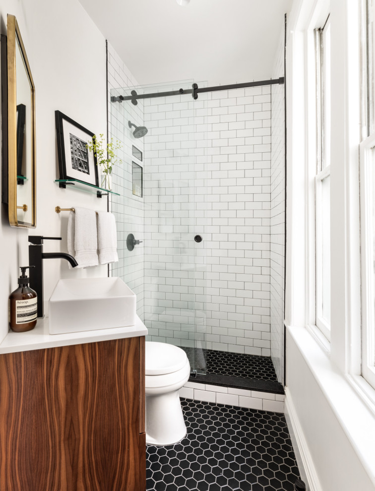Inredning av ett modernt mellanstort vit vitt badrum med dusch, med skåp i mellenmörkt trä, en dusch i en alkov, vit kakel, tunnelbanekakel, vita väggar, klinkergolv i porslin, ett fristående handfat, svart golv och dusch med skjutdörr