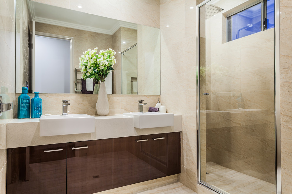 Ejemplo de cuarto de baño actual con armarios con paneles lisos, puertas de armario de madera en tonos medios, paredes beige y lavabo encastrado