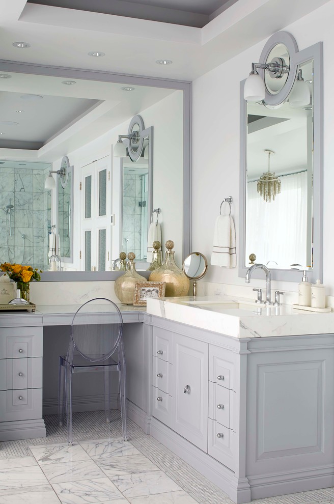 Cette photo montre une salle de bain principale chic avec un lavabo intégré, des portes de placard grises, un plan de toilette en marbre, un carrelage blanc, un carrelage de pierre, un mur violet et un placard avec porte à panneau surélevé.