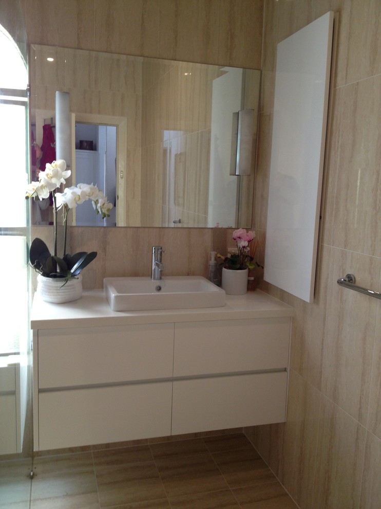 На фото: ванная комната среднего размера в стиле модернизм с накладной раковиной, белыми фасадами, столешницей из гранита, двойным душем, унитазом-моноблоком, бежевой плиткой, керамической плиткой, бежевыми стенами, полом из керамической плитки и душевой кабиной с