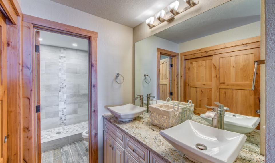 Example of a small mountain style master beige tile and porcelain tile porcelain tile and beige floor bathroom design in Denver with raised-panel cabinets, white cabinets, a two-piece toilet, beige walls, a vessel sink, granite countertops, a hinged shower door and white countertops