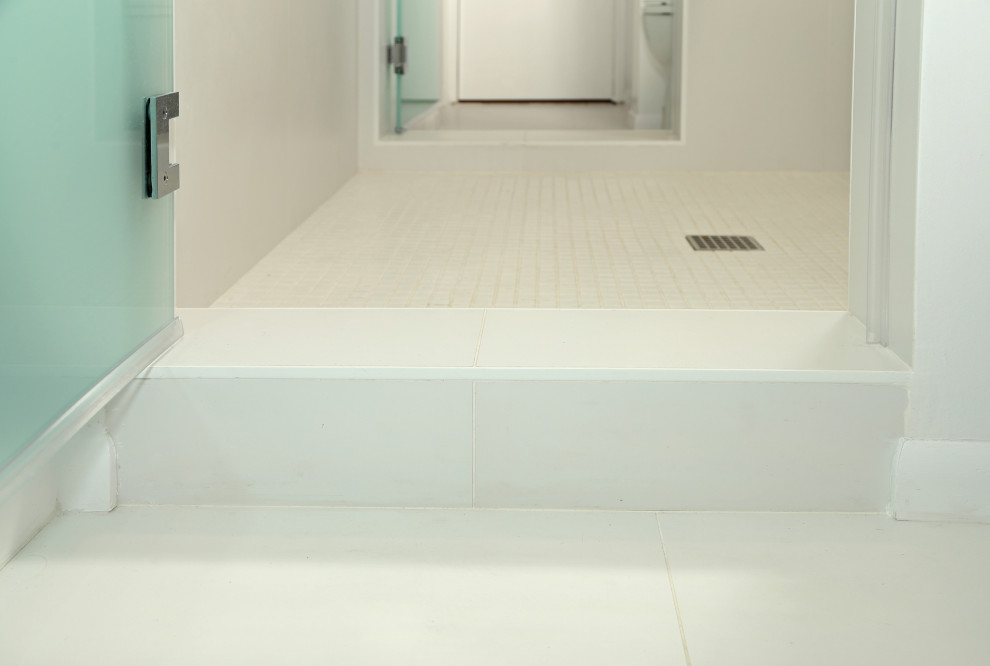 Bild på ett litet funkis vit vitt en-suite badrum, med släta luckor, vita skåp, en dubbeldusch, en toalettstol med separat cisternkåpa, vit kakel, porslinskakel, vita väggar, klinkergolv i porslin, ett nedsänkt handfat, bänkskiva i kvarts, vitt golv och dusch med gångjärnsdörr