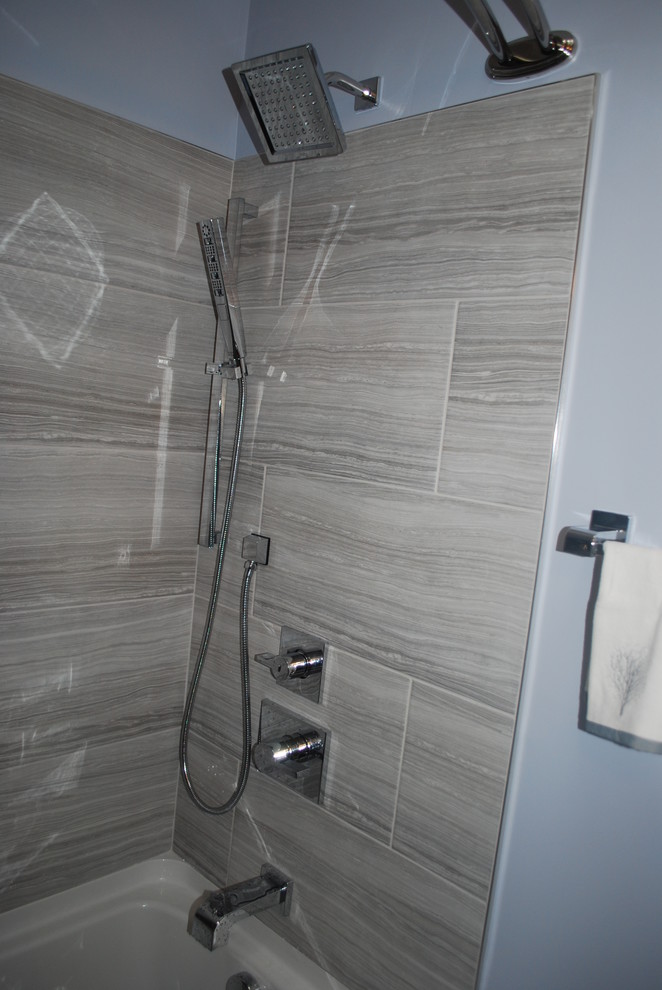 Inredning av ett litet badrum för barn, med vita skåp, en dusch/badkar-kombination, en bidé, grå kakel, keramikplattor, blå väggar, ett undermonterad handfat, marmorbänkskiva, dusch med duschdraperi, klinkergolv i porslin och grått golv