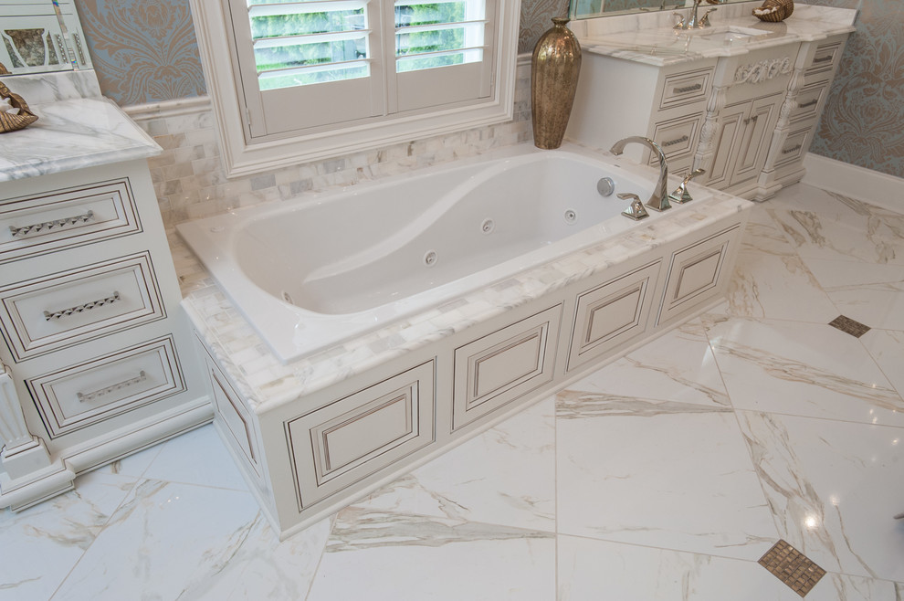 Inspiration for a traditional ensuite bathroom in Raleigh with recessed-panel cabinets, white cabinets, a built-in bath, white tiles, ceramic tiles, beige walls, marble flooring, a built-in sink and granite worktops.