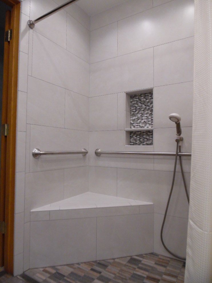 Kleines Klassisches Badezimmer mit bodengleicher Dusche, Urinal, weißen Fliesen, Porzellanfliesen, grauer Wandfarbe, Porzellan-Bodenfliesen, integriertem Waschbecken, Mineralwerkstoff-Waschtisch, buntem Boden und weißer Waschtischplatte in Milwaukee