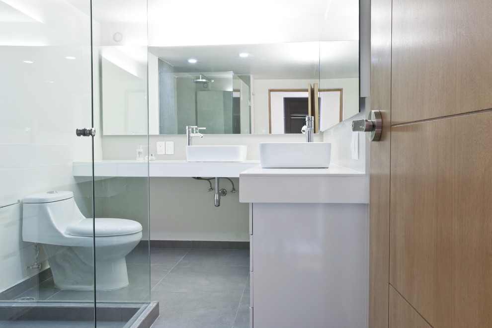 Idéer för att renovera ett funkis badrum, med ett fristående handfat, vita skåp, en hörndusch, en toalettstol med hel cisternkåpa och grå kakel