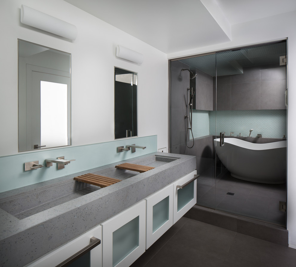 Large contemporary ensuite bathroom in Philadelphia with a trough sink, glass-front cabinets, white cabinets, concrete worktops, a freestanding bath, a two-piece toilet, grey tiles, ceramic tiles, white walls and ceramic flooring.