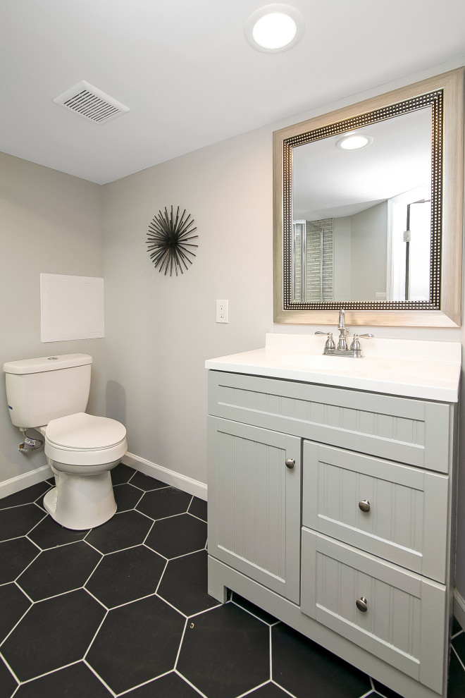 This is an example of a medium sized classic shower room bathroom in Philadelphia with shaker cabinets, grey cabinets, a corner bath, a corner shower, a two-piece toilet, grey tiles, porcelain tiles, grey walls, porcelain flooring, an integrated sink, engineered stone worktops, black floors, a hinged door and white worktops.