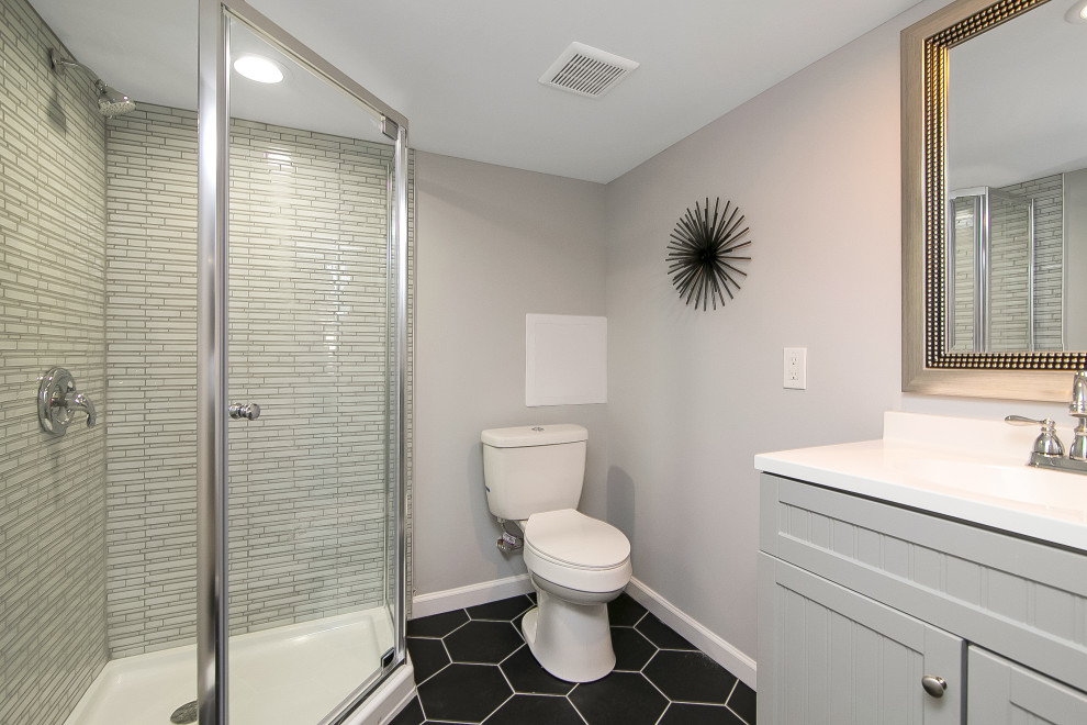 Example of a mid-sized classic 3/4 gray tile and porcelain tile porcelain tile and black floor bathroom design in Philadelphia with shaker cabinets, gray cabinets, a two-piece toilet, gray walls, an integrated sink, quartz countertops, a hinged shower door and white countertops