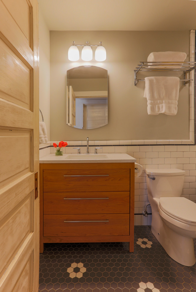 Idéer för ett litet amerikanskt badrum, med möbel-liknande, skåp i mellenmörkt trä, ett badkar med tassar, en dusch/badkar-kombination, en toalettstol med hel cisternkåpa, vit kakel, porslinskakel, grå väggar, klinkergolv i porslin, ett undermonterad handfat, bänkskiva i kvarts, flerfärgat golv och dusch med duschdraperi