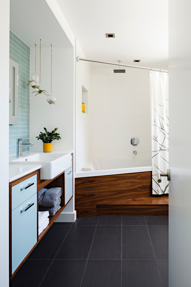 Cette photo montre une salle de bain tendance avec un lavabo posé, un placard à porte plane, des portes de placard bleues, un carrelage bleu, un sol noir et un plan de toilette blanc.