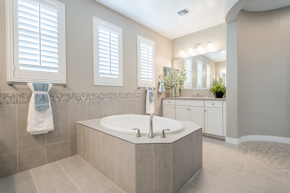 This is an example of a medium sized contemporary ensuite bathroom in Phoenix with recessed-panel cabinets, white cabinets, a built-in bath, an alcove shower, beige tiles, ceramic tiles, beige walls, ceramic flooring, a submerged sink, solid surface worktops, beige floors, beige worktops and an open shower.