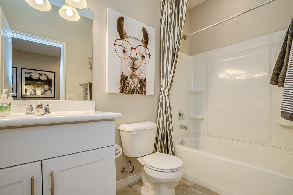 Inspiration for a medium sized contemporary family bathroom in Phoenix with recessed-panel cabinets, white cabinets, an alcove bath, a shower/bath combination, white tiles, ceramic tiles, beige walls, light hardwood flooring, an integrated sink, solid surface worktops, grey floors, a shower curtain and white worktops.