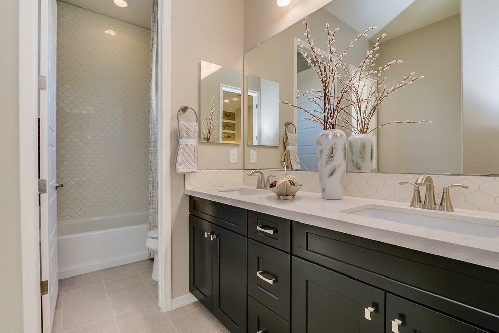 This is an example of a medium sized contemporary family bathroom in Phoenix with recessed-panel cabinets, black cabinets, an alcove bath, a shower/bath combination, beige tiles, ceramic tiles, beige walls, ceramic flooring, a submerged sink, solid surface worktops, beige floors and a shower curtain.