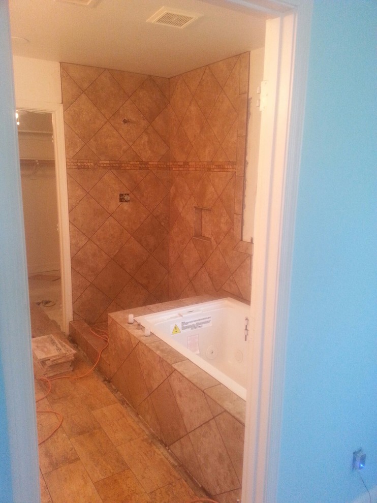 Foto di una stanza da bagno classica di medie dimensioni con lavabo sottopiano, nessun'anta, ante beige, vasca/doccia, WC monopezzo, piastrelle marroni, piastrelle in pietra, pareti beige e pavimento in travertino