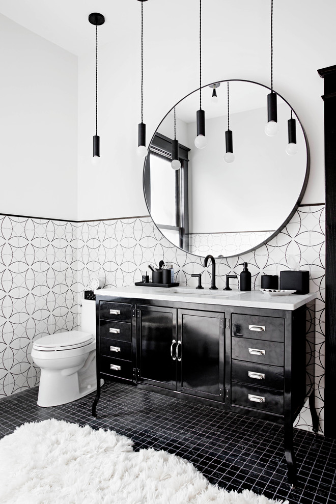 Klassisk inredning av ett badrum, med svarta skåp, svart och vit kakel, vita väggar, ett undermonterad handfat, svart golv och skåp i shakerstil