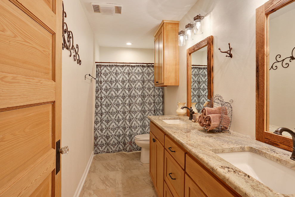This is an example of a medium sized traditional bathroom in New Orleans with shaker cabinets, medium wood cabinets, an alcove bath, a shower/bath combination, white walls, porcelain flooring, a submerged sink, granite worktops, grey floors and a shower curtain.