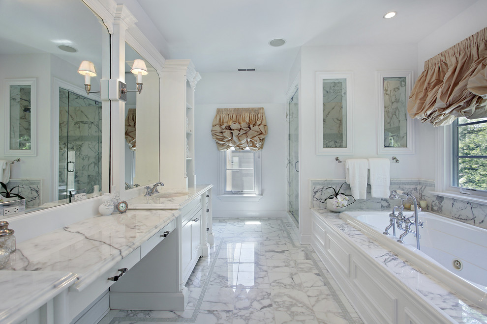 Cette image montre une salle de bain principale traditionnelle avec un placard à porte shaker, des portes de placard blanches, une douche d'angle, un carrelage blanc, un mur blanc, un sol en marbre, un lavabo encastré, un plan de toilette en marbre et du carrelage en marbre.