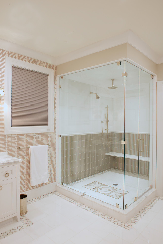 На фото: главная ванная комната среднего размера в стиле неоклассика (современная классика) с фасадами островного типа, белыми фасадами, угловым душем, коричневой плиткой, белой плиткой, бежевыми стенами, полом из керамической плитки, врезной раковиной, мраморной столешницей, белым полом и душем с распашными дверями