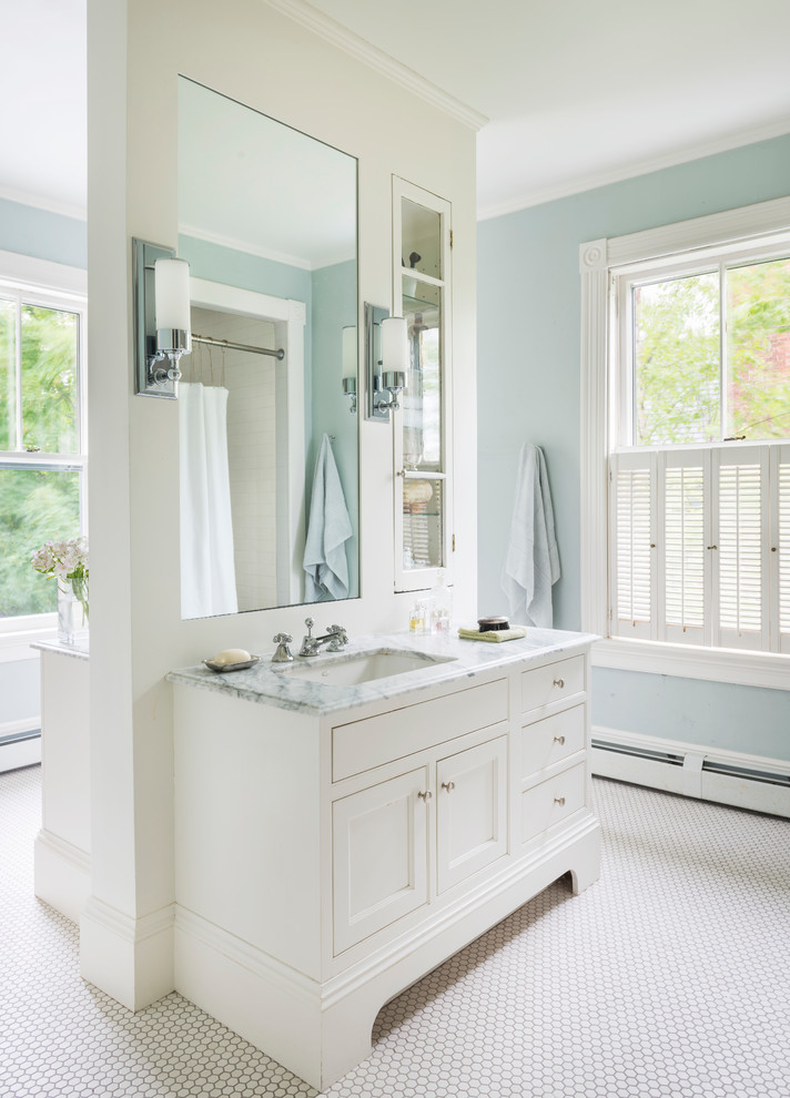 Modelo de cuarto de baño principal clásico grande con armarios con paneles empotrados, puertas de armario blancas, paredes azules, suelo con mosaicos de baldosas, encimera de mármol, lavabo bajoencimera y suelo blanco
