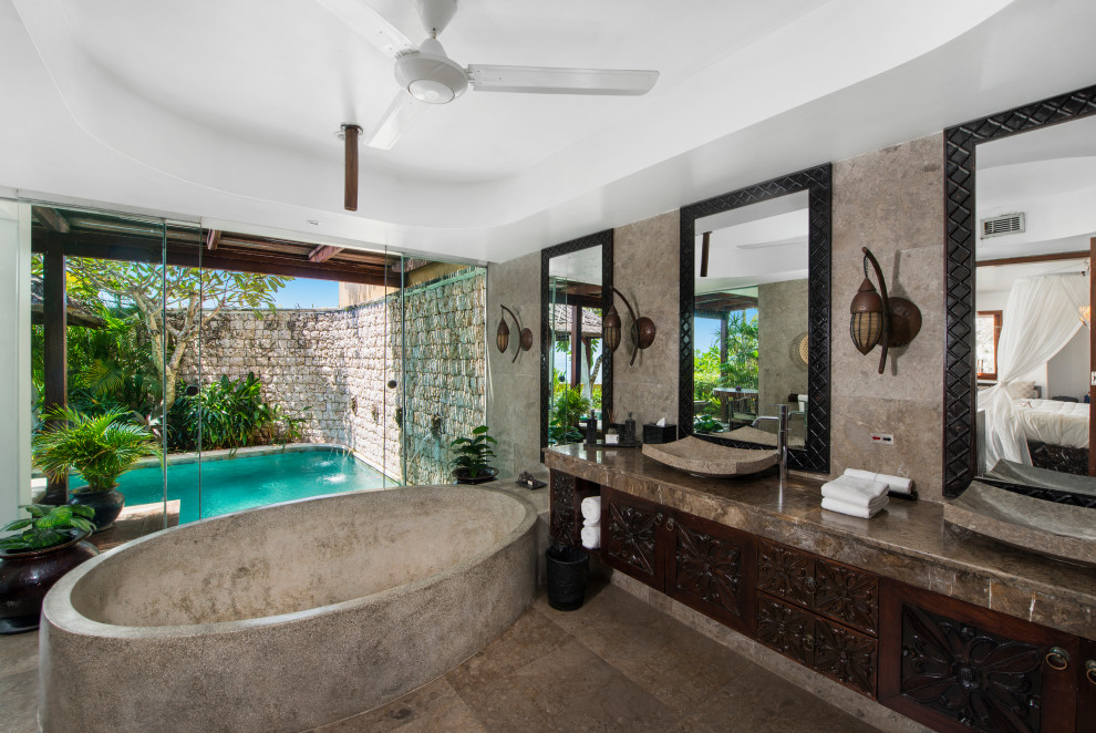 Esempio di una stanza da bagno tropicale con ante in legno bruno, vasca freestanding, lavabo a bacinella, pavimento marrone, top marrone, due lavabi e mobile bagno incassato
