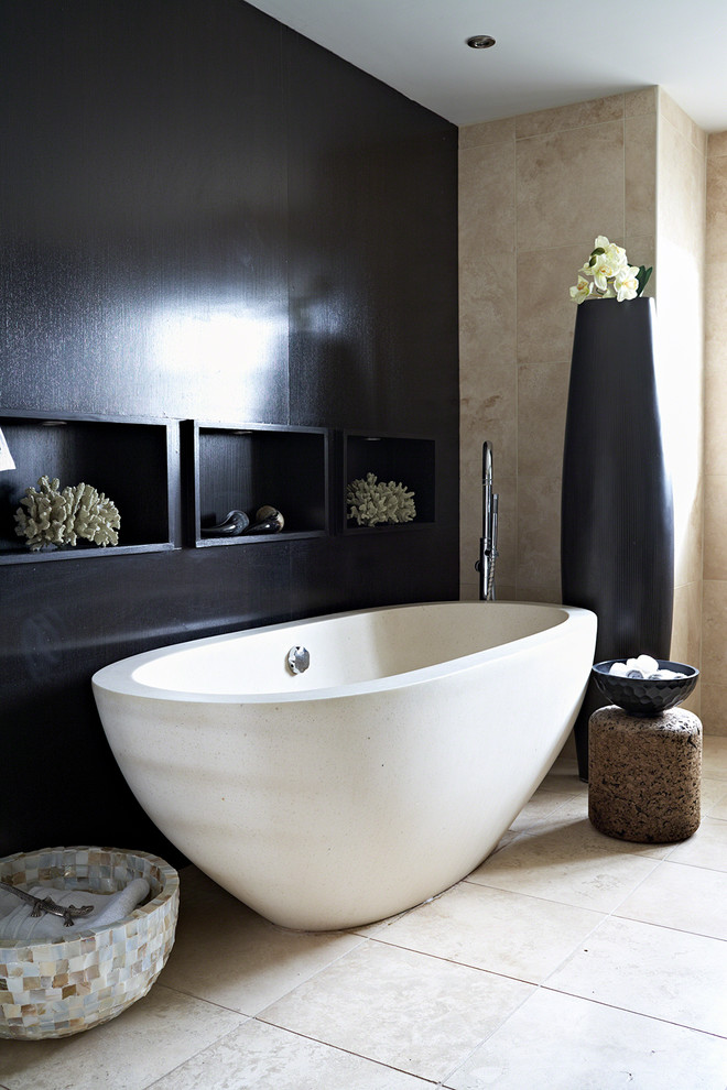 Inspiration pour une salle de bain design avec une baignoire indépendante, un carrelage beige, un mur noir et du carrelage en travertin.