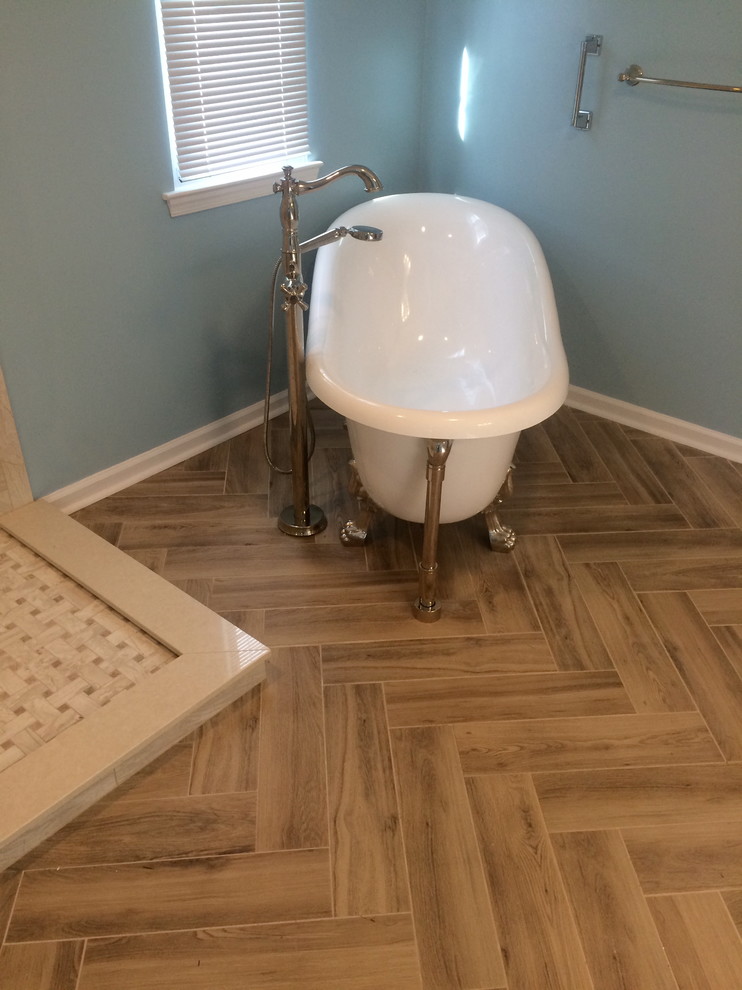 Cette image montre une salle de bain vintage de taille moyenne avec une baignoire sur pieds, un mur bleu et un sol en bois brun.