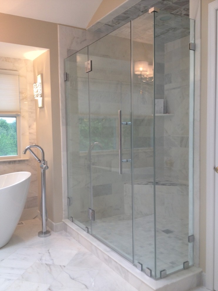 Idée de décoration pour une grande douche en alcôve principale design avec une baignoire indépendante, un mur beige et un sol en marbre.
