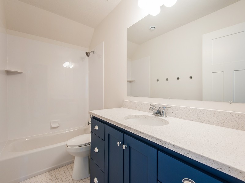 Aménagement d'une salle de bain craftsman de taille moyenne pour enfant avec un placard avec porte à panneau encastré, des portes de placard bleues, un plan de toilette en quartz, une baignoire posée, un carrelage blanc, des carreaux de céramique et un sol en carrelage de céramique.