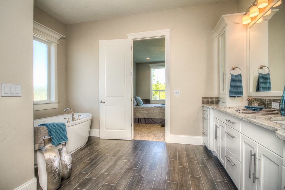 Immagine di una stanza da bagno padronale minimalista con ante con riquadro incassato, ante bianche, top in granito, vasca freestanding, doccia doppia e WC monopezzo