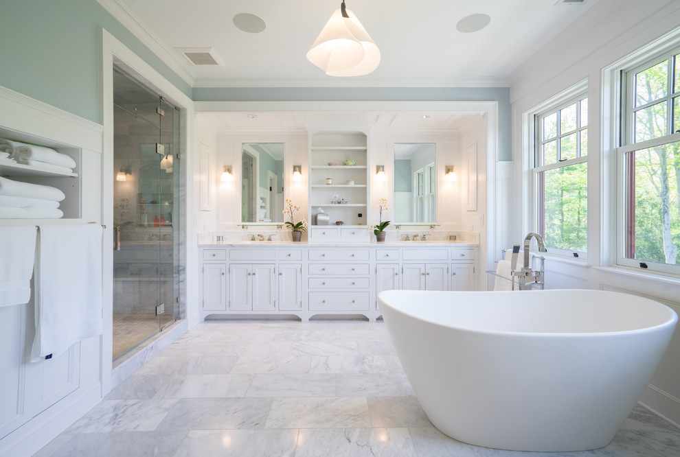 Inspiration for a classic bathroom in New York with shaker cabinets, white cabinets, a freestanding bath, an alcove shower, white tiles, white walls, grey floors and a hinged door.