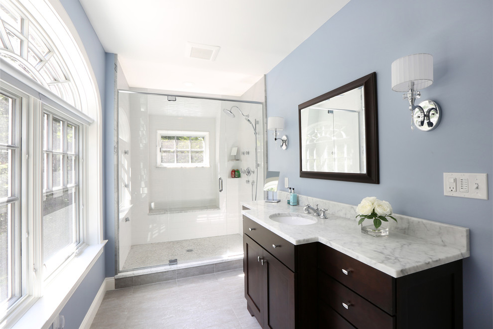 Inspiration for a large timeless master porcelain tile and white tile porcelain tile alcove shower remodel in Boston with flat-panel cabinets, dark wood cabinets, blue walls, an undermount sink, marble countertops, a one-piece toilet, a hinged shower door and gray countertops